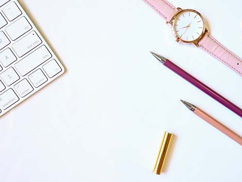 leisure activities pink pen on table with round gold-colored analog watch brass section